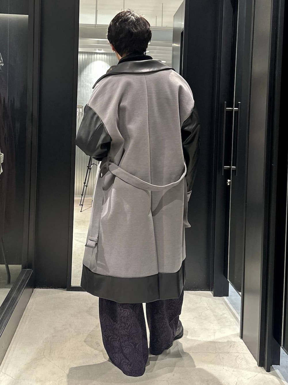 グレー系のトレンチコート、ブラック系のローファー、ブラック系のニット/セーターを着用したメンズの秋コーディネートの5枚目の写真