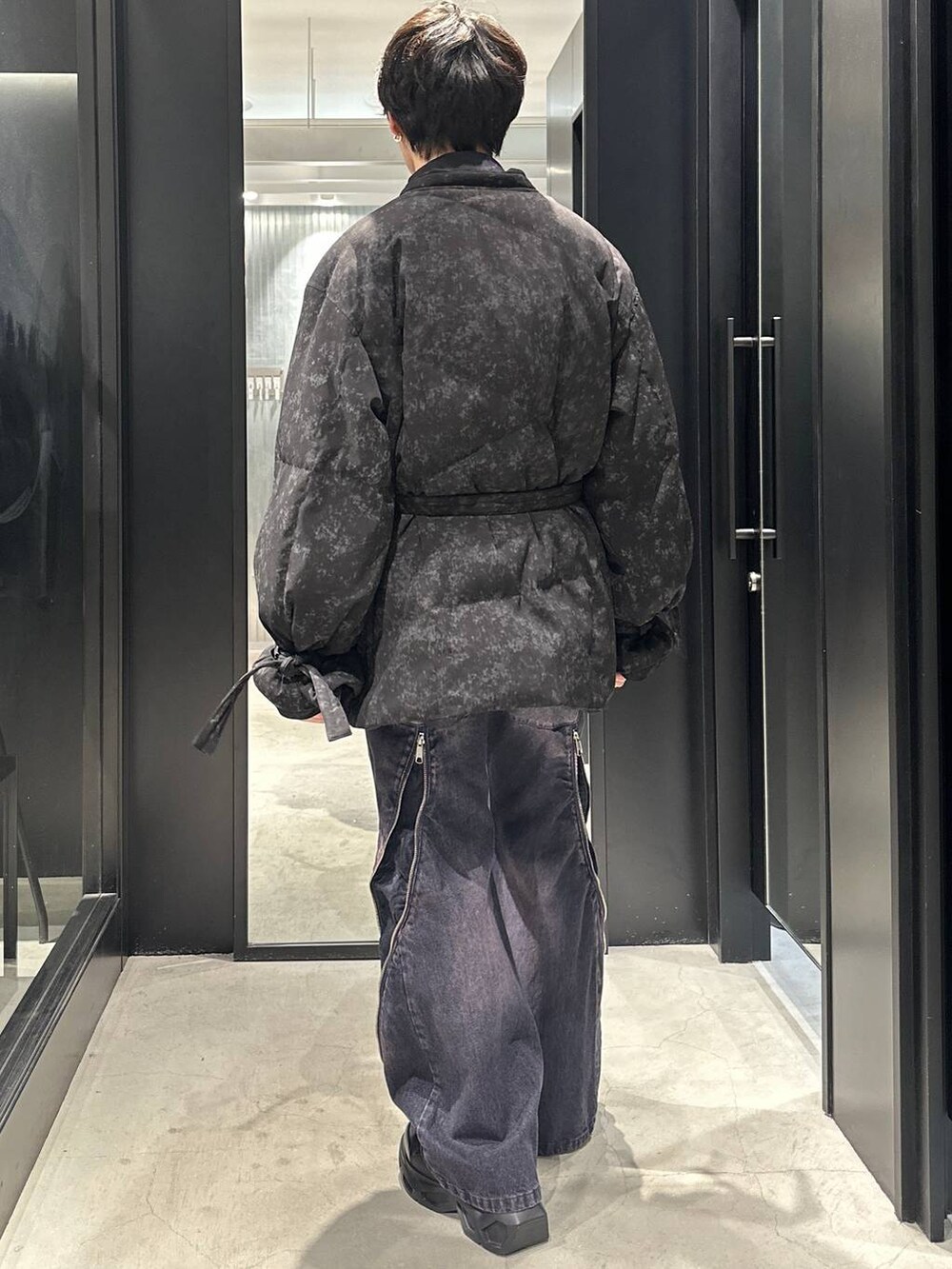 ブラック系のスニーカー、グレー系のダウンジャケット/コート、パープル系のデニムパンツを着用したメンズの冬コーディネートの3枚目の写真