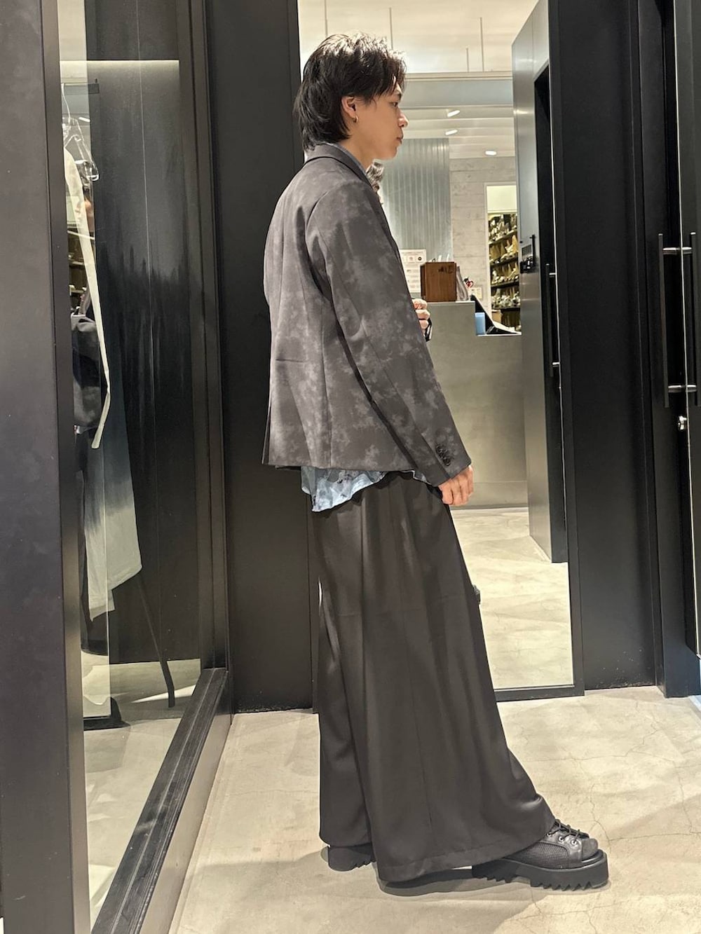 グレー系のテーラードジャケット、ブラック系のネクタイ、ブラック系のサンダルを着用したメンズの春コーディネートの4枚目の写真