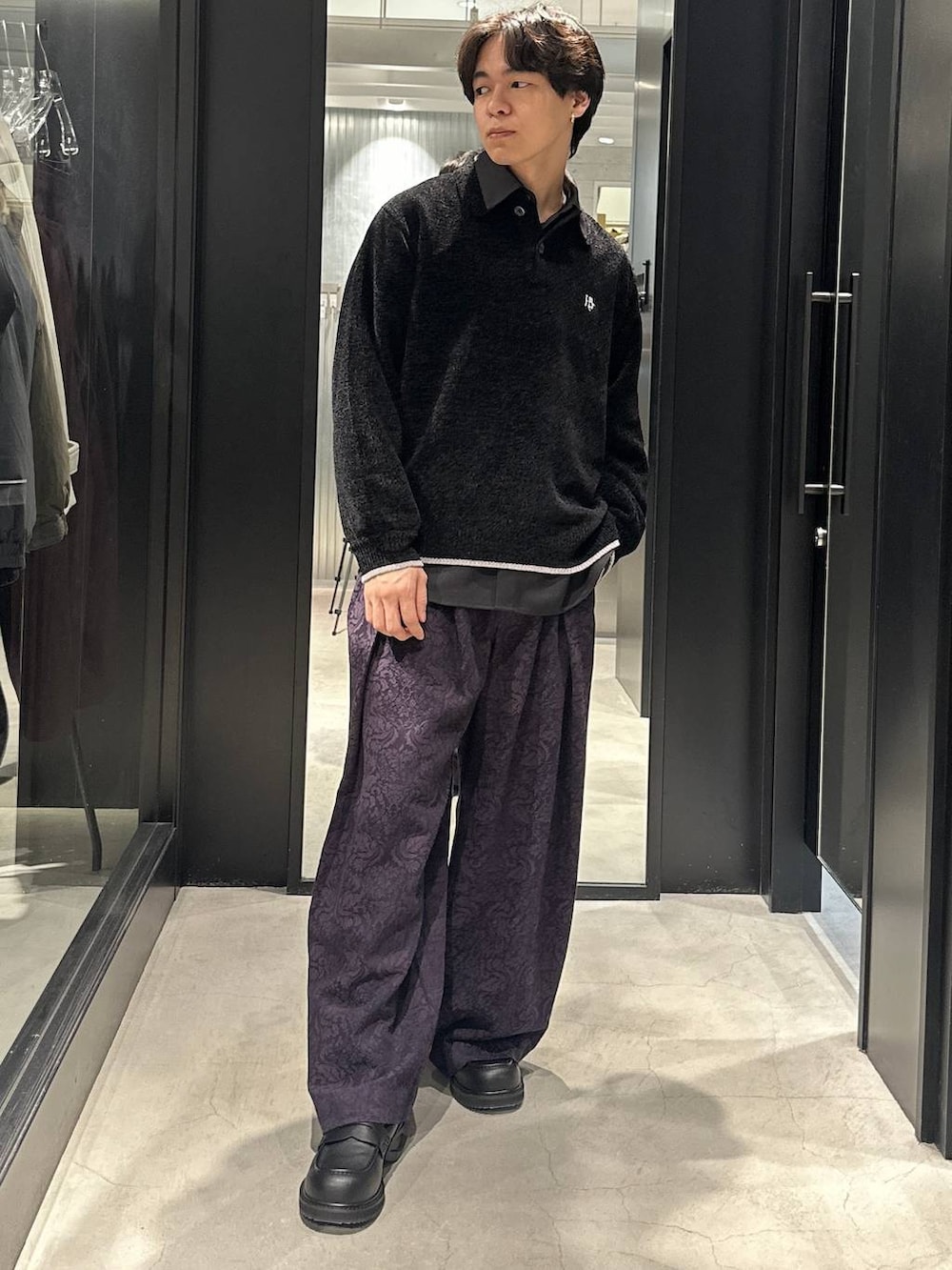 グレー系のトレンチコート、ブラック系のローファー、ブラック系のニット/セーターを着用したメンズの秋コーディネートの6枚目の写真