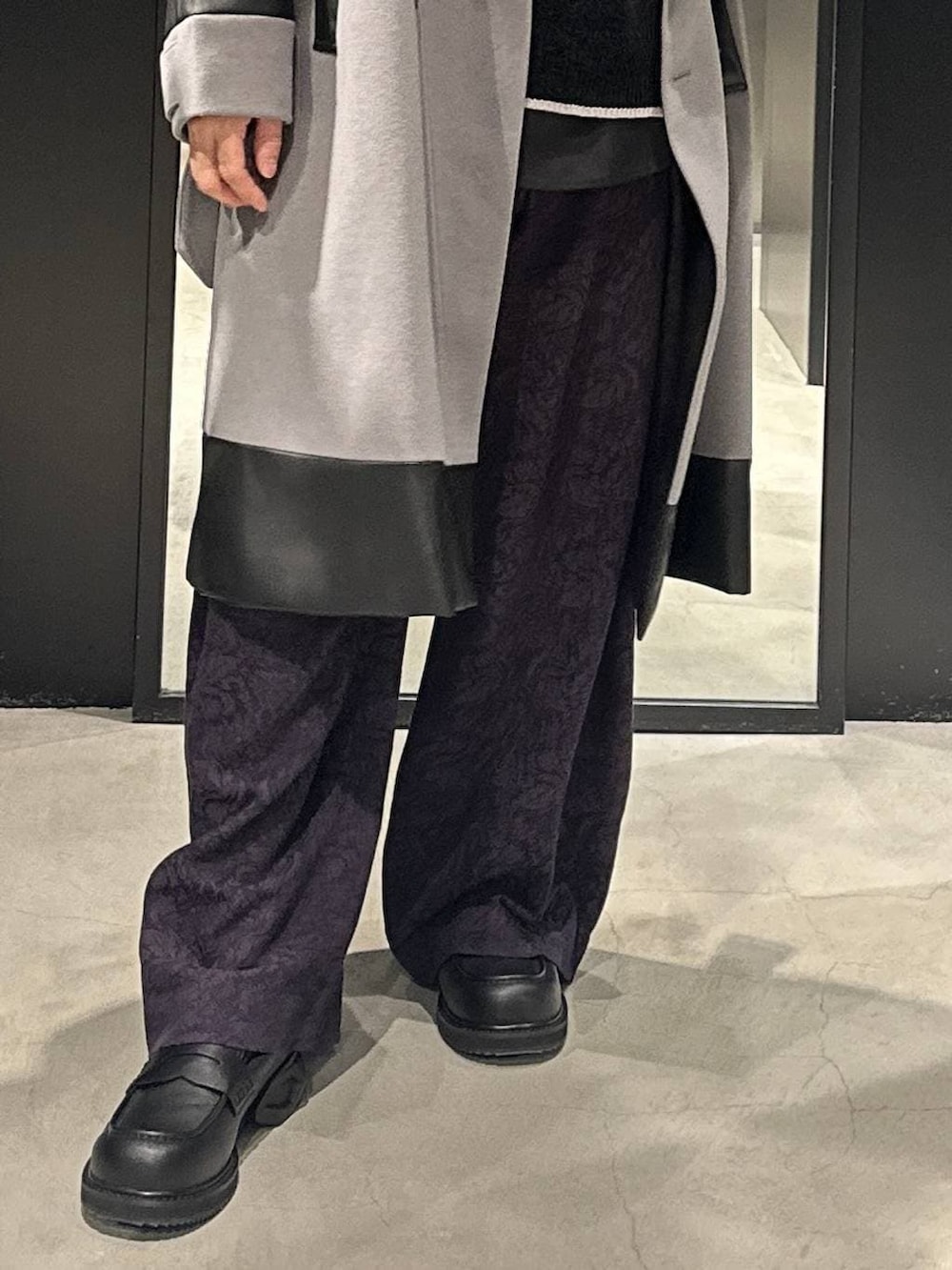 グレー系のトレンチコート、ブラック系のローファー、ブラック系のニット/セーターを着用したメンズの秋コーディネートの3枚目の写真