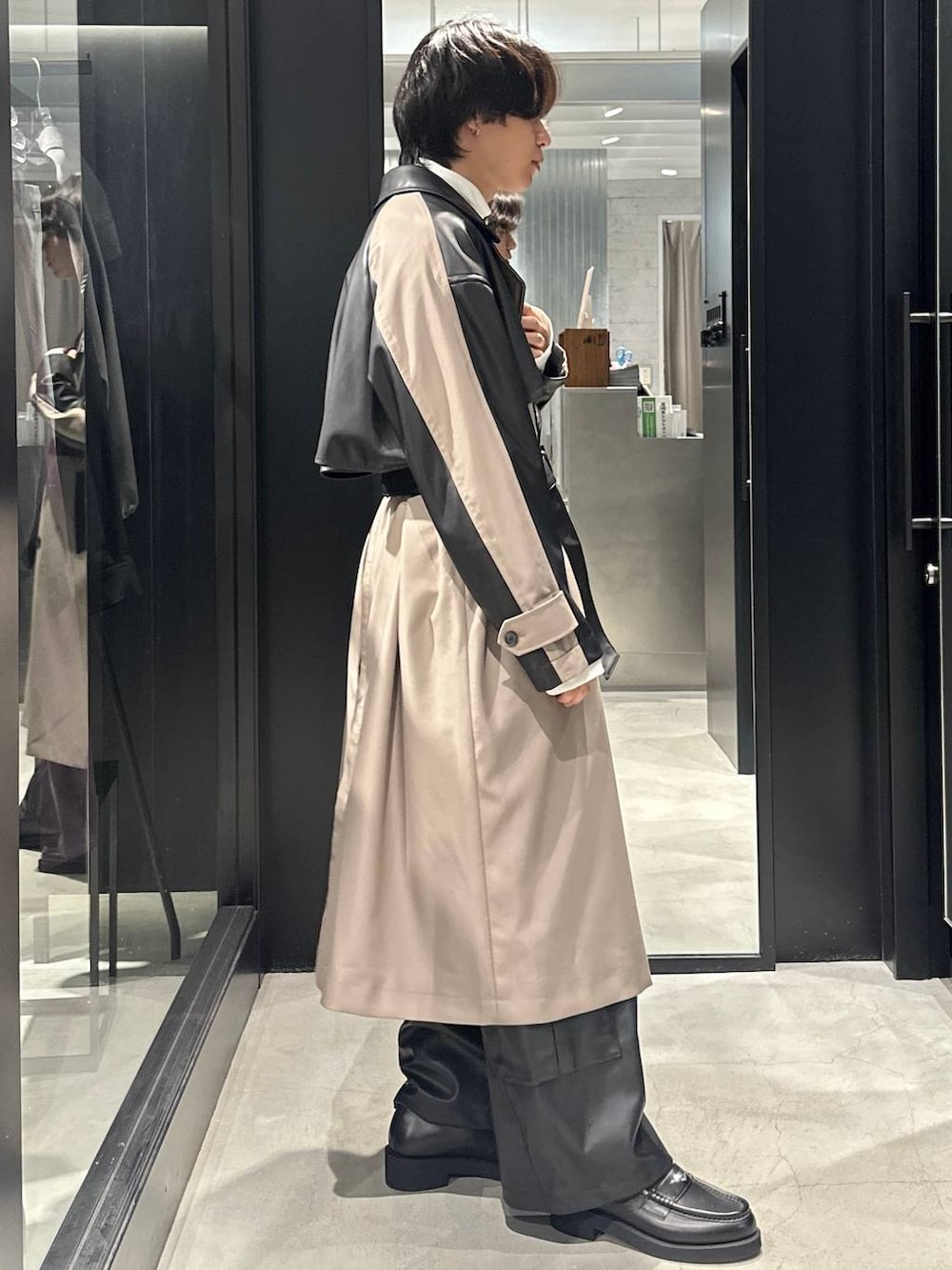 ブラック系のカーゴパンツ、ブラック系のローファー、ベージュ系のトレンチコートを着用したメンズの秋コーディネートの2枚目の写真