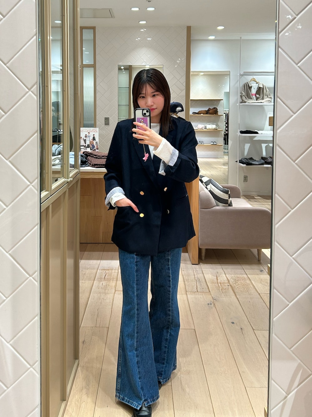 ブルー系のテーラードジャケット、ブルー系のデニムパンツ、ブラック系のショルダーバッグを着用したレディースの秋コーディネートの2枚目の写真