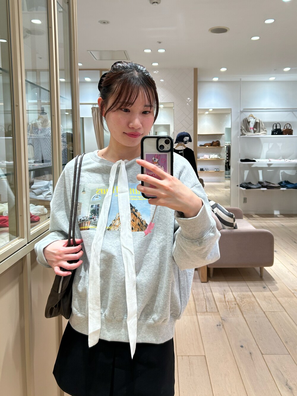 グレー系のスウェット、ホワイト系のシャツ/ブラウス、ブラック系のスカートを着用したレディースの秋コーディネートの3枚目の写真