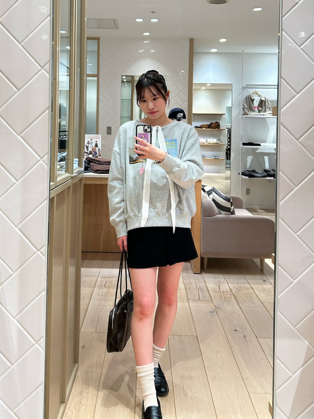 グレー系のスウェット、ホワイト系のシャツ/ブラウス、ブラック系のスカートを着用したレディースの秋コーディネートの2枚目の写真