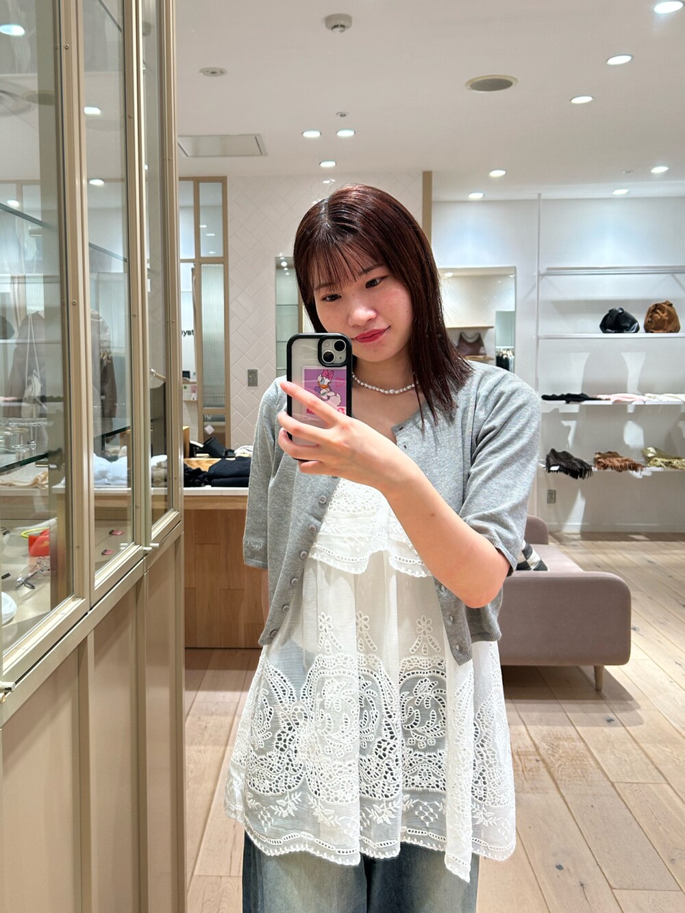 ホワイト系のシャツ/ブラウス、グレー系のカーディガン/ボレロ、ブルー系のデニムパンツを着用したレディースの秋コーディネートの2枚目の写真