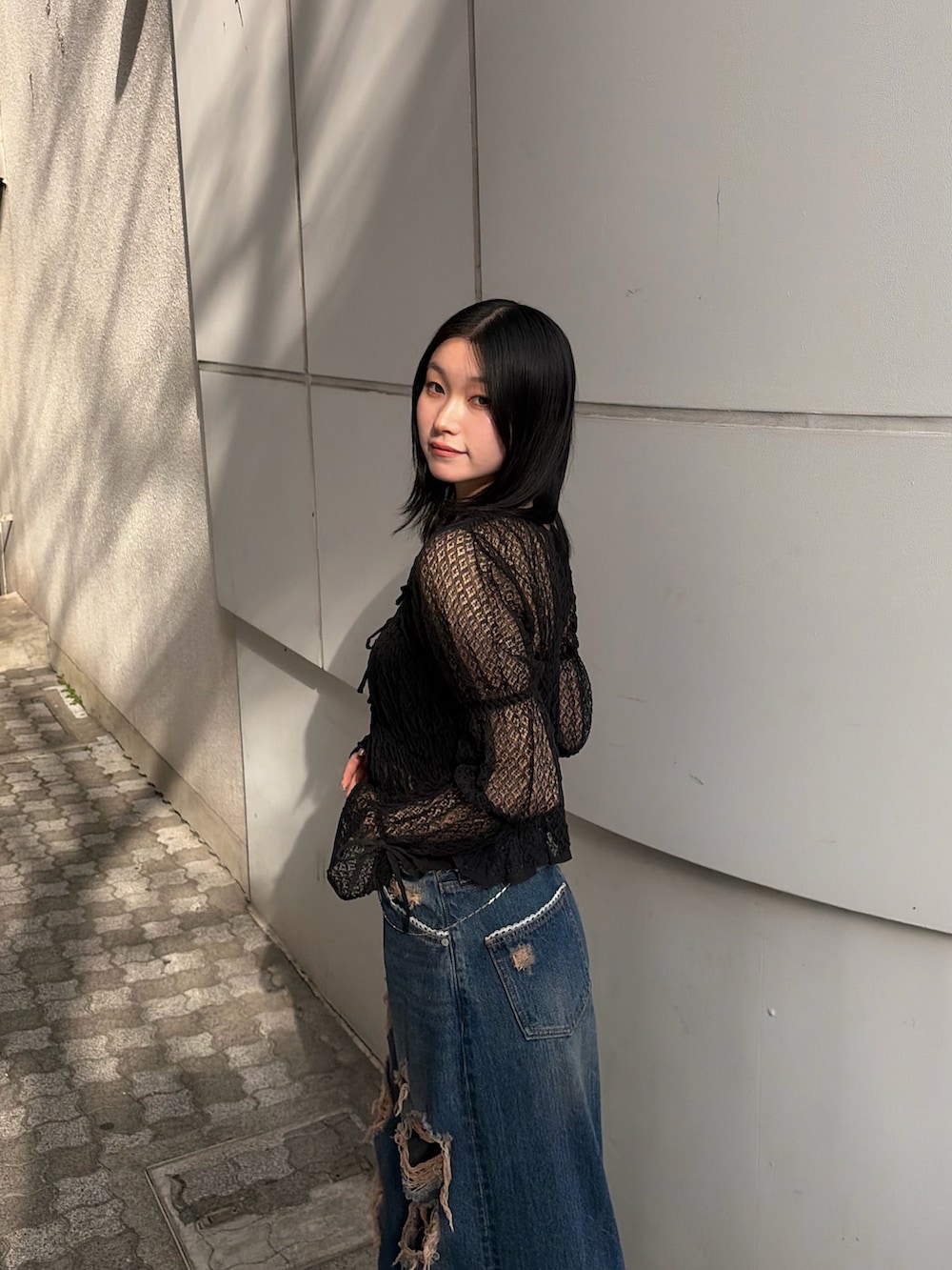 ブラック系のニット/セーター、ブルー系のデニムパンツ、ブラック系のブーツを着用したレディースの春コーディネートの6枚目の写真