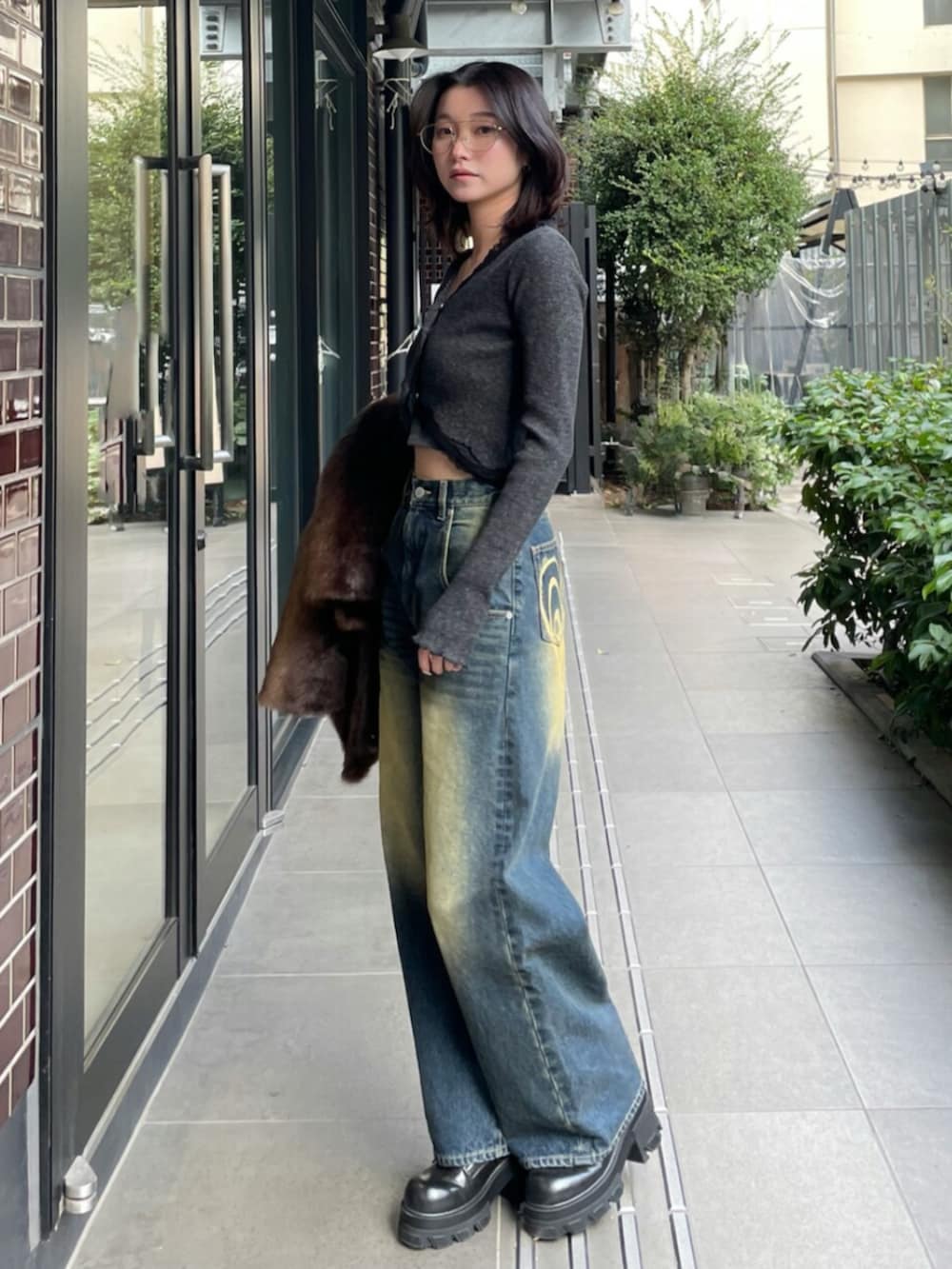 ブラック系のブーツ、ブラック系のニット/セーター、ブルー系のデニムパンツを着用したレディースの冬コーディネートの2枚目の写真