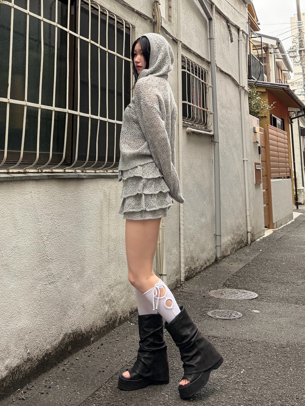 グレー系のパーカー、グレー系のスカート、ブラック系のサンダルを着用したレディースの春コーディネートの2枚目の写真