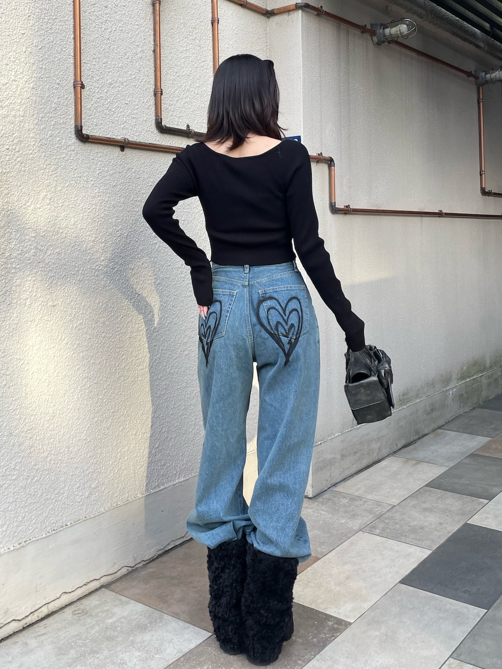 ブラック系のニット/セーター、ブルー系のデニムパンツ、ブラック系のブーツを着用したレディースの冬コーディネートの4枚目の写真