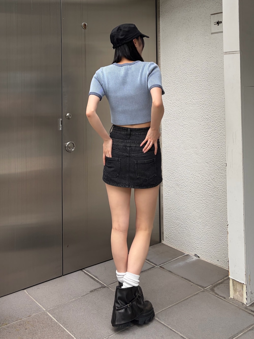 ブルー系のニット/セーター、ブラック系のスカート、ブラック系のブーツを着用したレディースの夏コーディネートの3枚目の写真