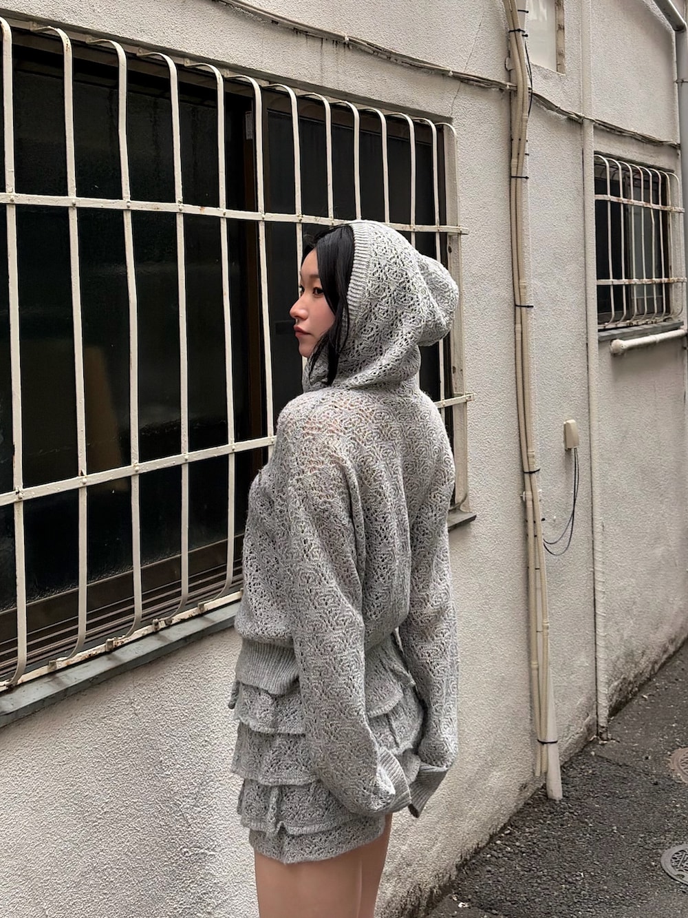 グレー系のパーカー、グレー系のスカート、ブラック系のサンダルを着用したレディースの春コーディネートの5枚目の写真