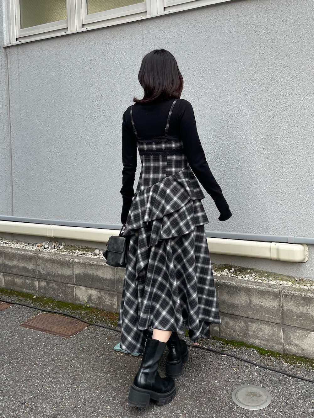 ブラック系のニット/セーター、ブラック系のワンピース、ブラック系のハンドバッグを着用したレディースの冬コーディネートの3枚目の写真