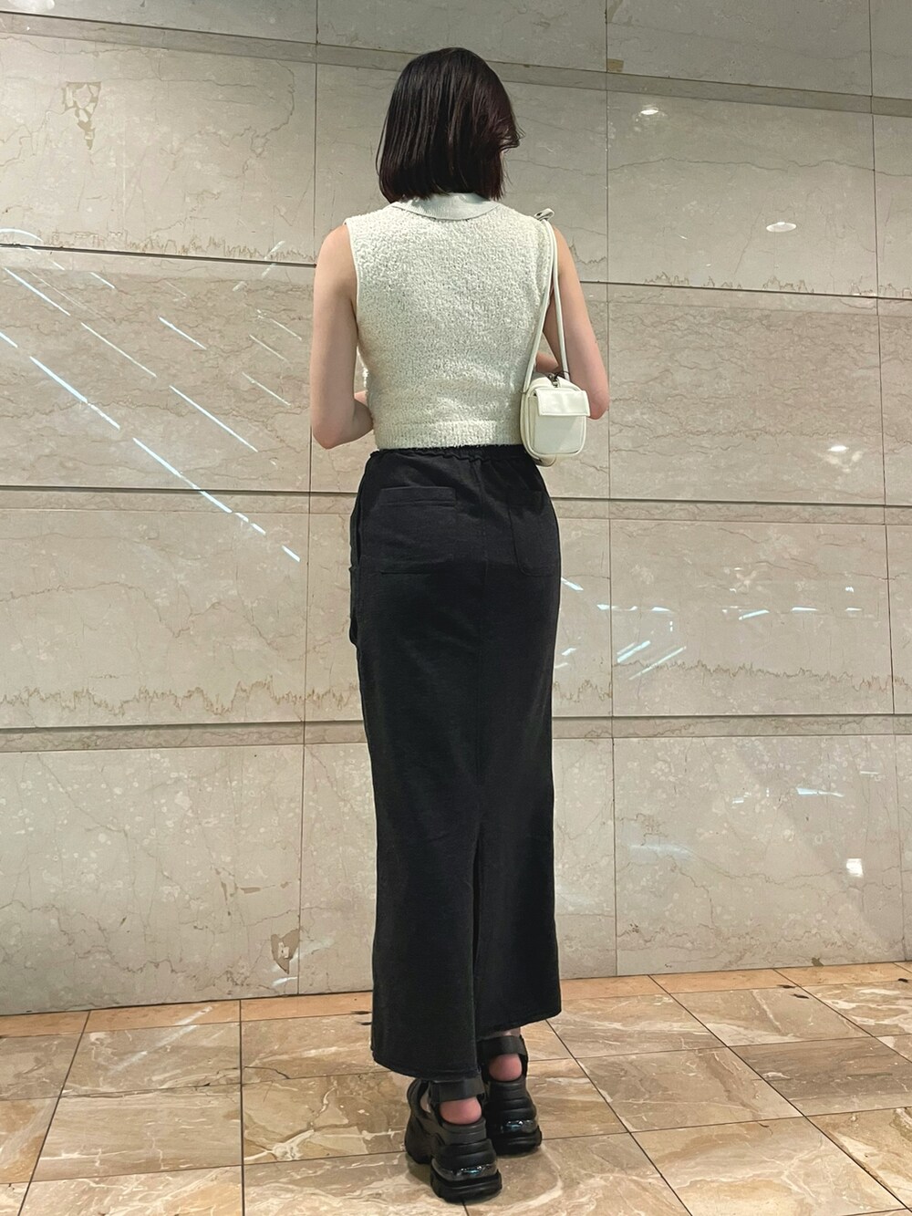 ホワイト系のニット/セーター、ブラック系のスカート、ホワイト系のハンドバッグを着用したレディースの夏コーディネートの4枚目の写真