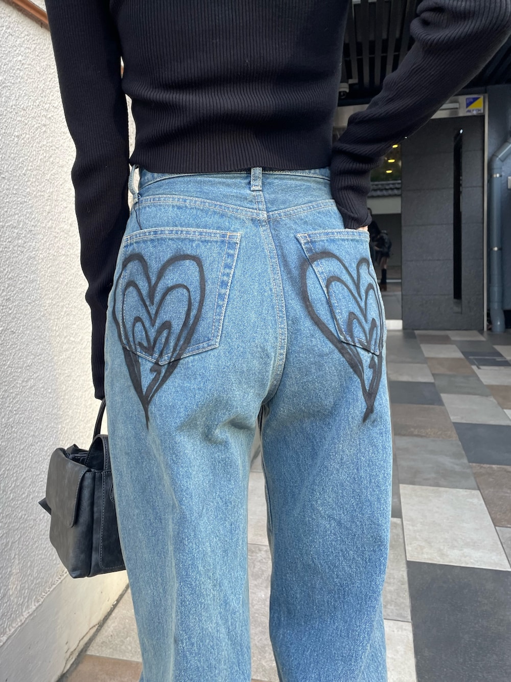 ブラック系のニット/セーター、ブルー系のデニムパンツ、ブラック系のブーツを着用したレディースの冬コーディネートの5枚目の写真