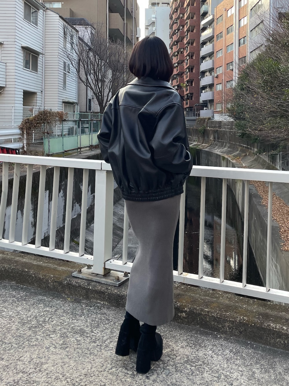 グレー系のワンピース、ブラック系のブルゾン、ブラック系のブーツを着用したレディースの冬コーディネートの3枚目の写真