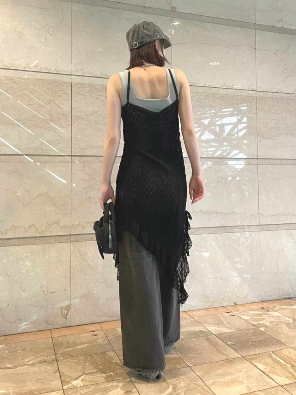 グレー系のニット/セーター、ブラック系のワンピース、ブラック系のデニムパンツを着用したレディースの夏コーディネートの3枚目の写真