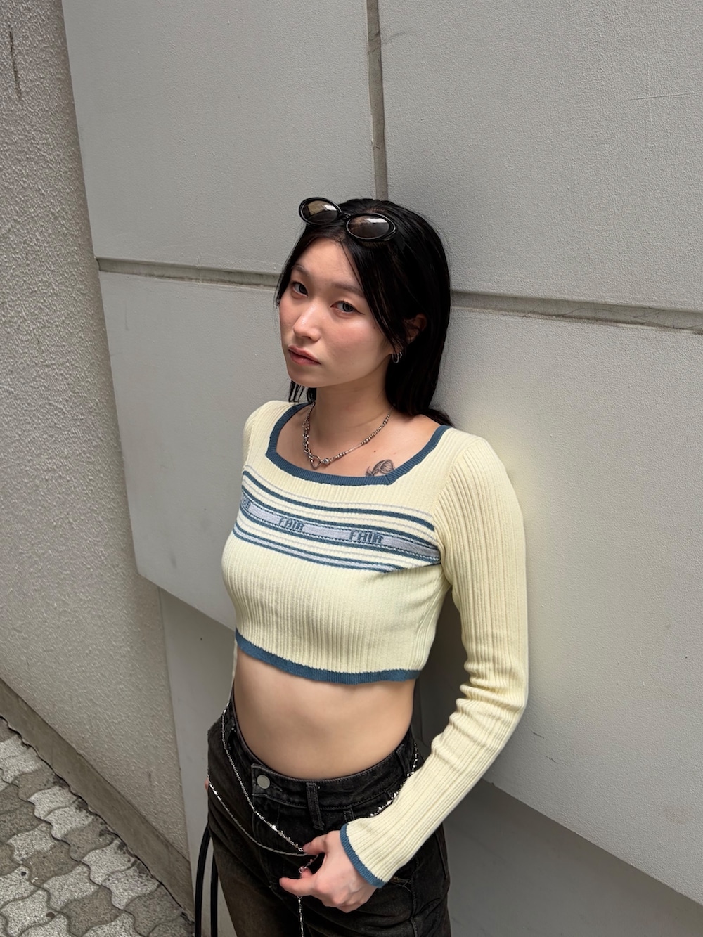 ホワイト系のニット/セーター、ブラック系のショルダーバッグ、ブラック系のデニムパンツを着用したレディースの秋コーディネートの4枚目の写真