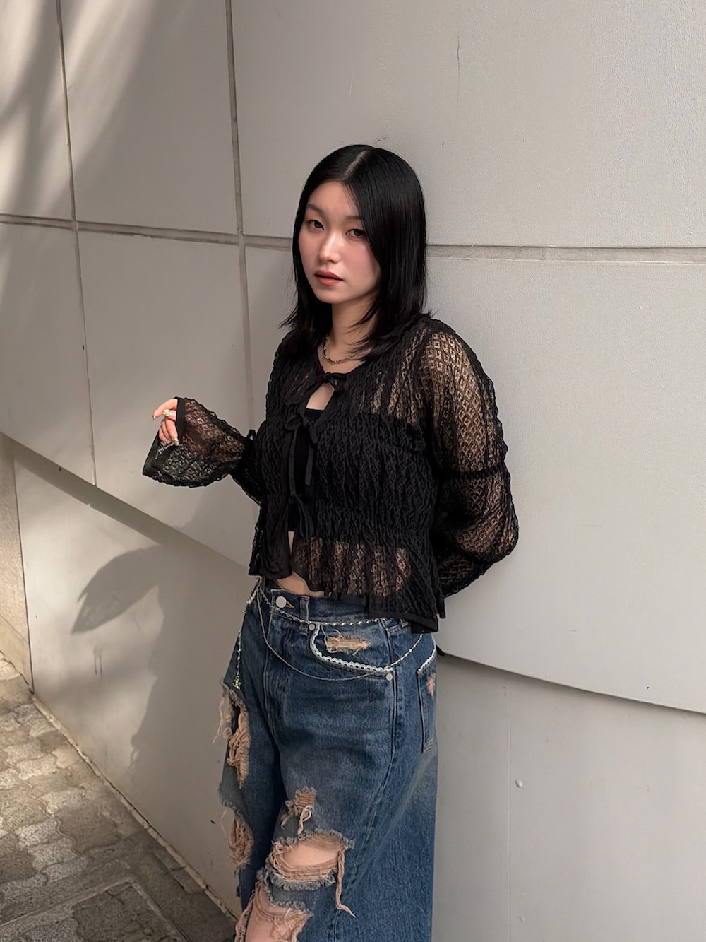 ブラック系のニット/セーター、ブルー系のデニムパンツ、ブラック系のブーツを着用したレディースの春コーディネートの5枚目の写真