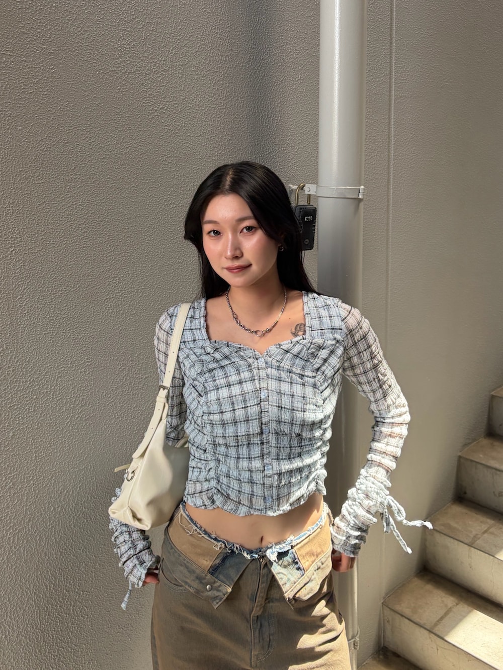 ブルー系のTシャツ/カットソー、ブラウン系のデニムパンツ、ホワイト系のハンドバッグを着用したレディースの秋コーディネートの5枚目の写真