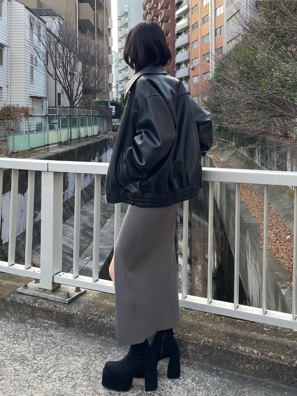 グレー系のワンピース、ブラック系のブルゾン、ブラック系のブーツを着用したレディースの冬コーディネートの2枚目の写真