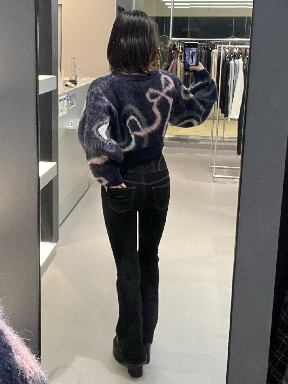 ブルー系のニット/セーター、ブラック系のデニムパンツ、ブラック系のブーツを着用したレディースの秋コーディネートの3枚目の写真
