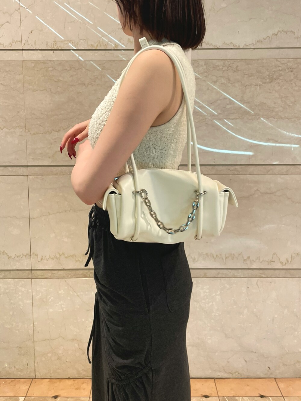 ホワイト系のニット/セーター、ブラック系のスカート、ホワイト系のハンドバッグを着用したレディースの夏コーディネートの5枚目の写真