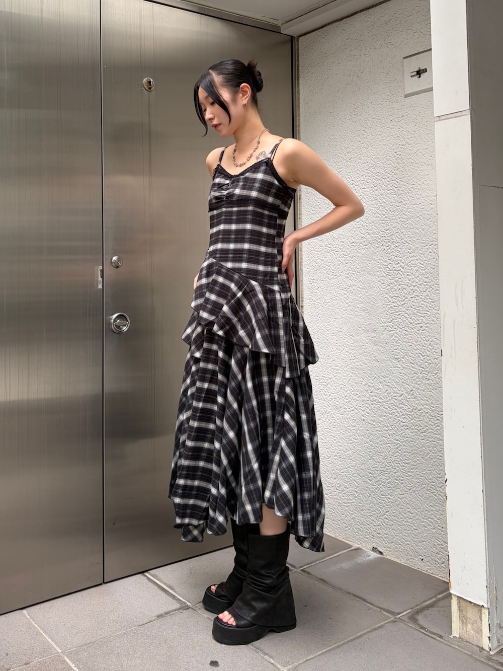 ブラック系のワンピース、ブラック系のサンダル、シルバー系のピアス(両耳用)を着用したレディースの夏コーディネートの4枚目の写真