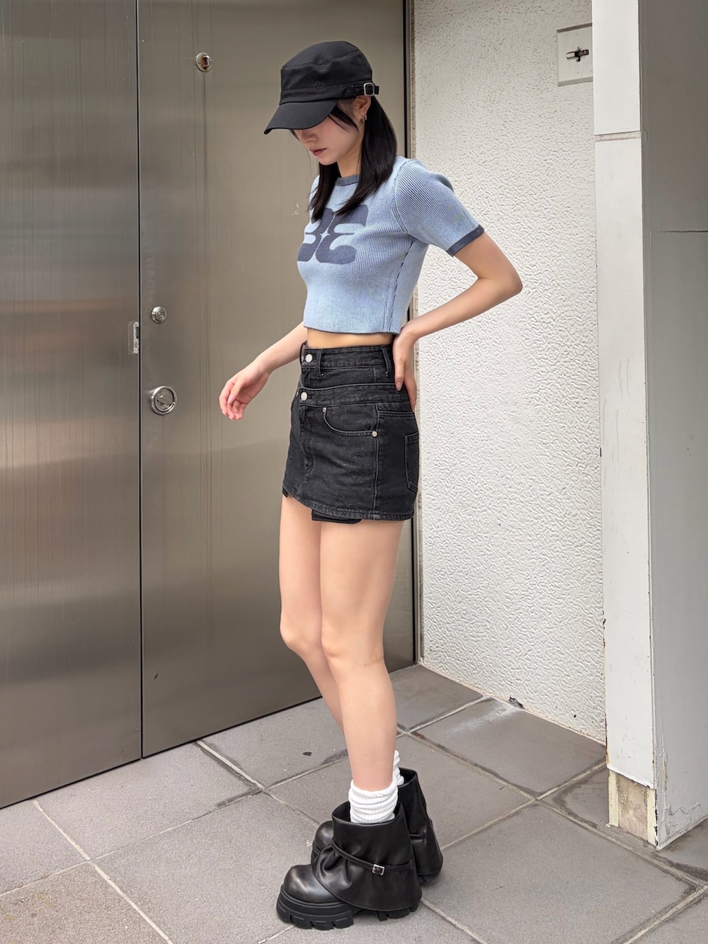 ブルー系のニット/セーター、ブラック系のスカート、ブラック系のブーツを着用したレディースの夏コーディネートの2枚目の写真