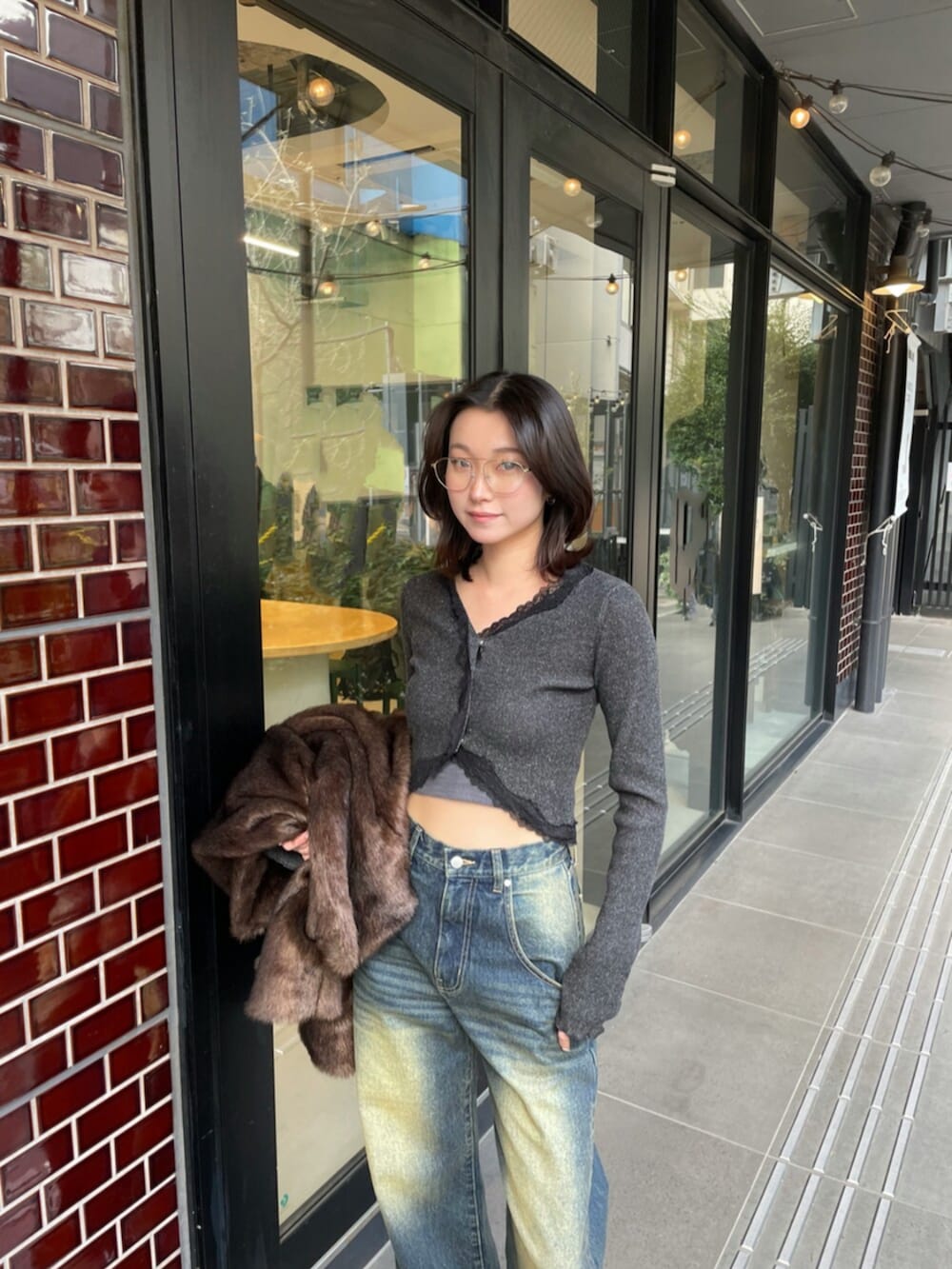 ブラック系のブーツ、ブラック系のニット/セーター、ブルー系のデニムパンツを着用したレディースの冬コーディネートの5枚目の写真