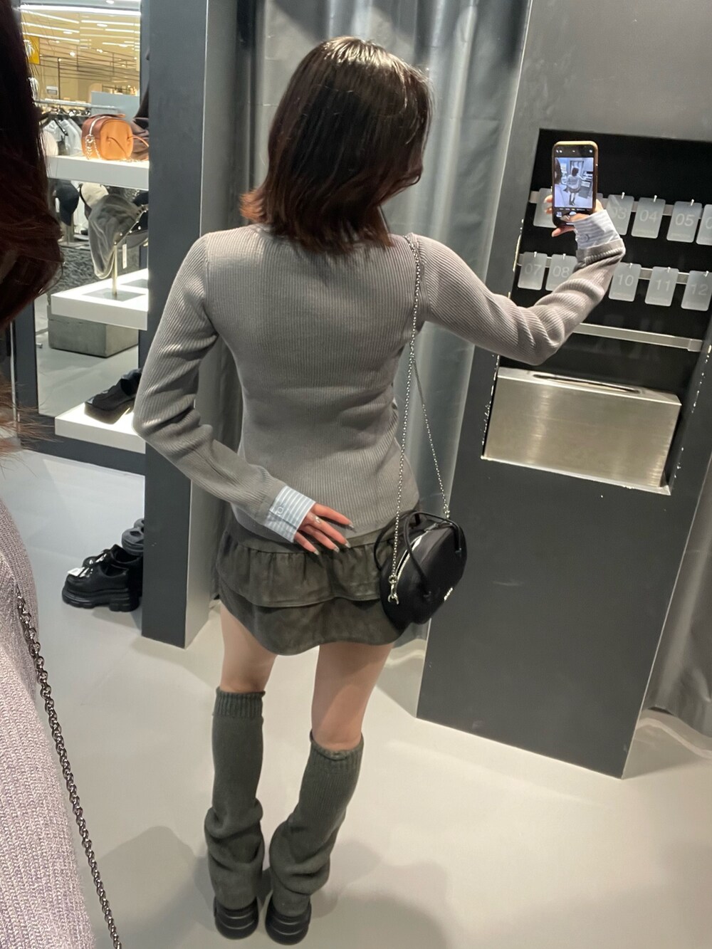 グレー系のニット/セーター、グレー系のスカート、ブラック系のローファーを着用したレディースの秋コーディネートの3枚目の写真