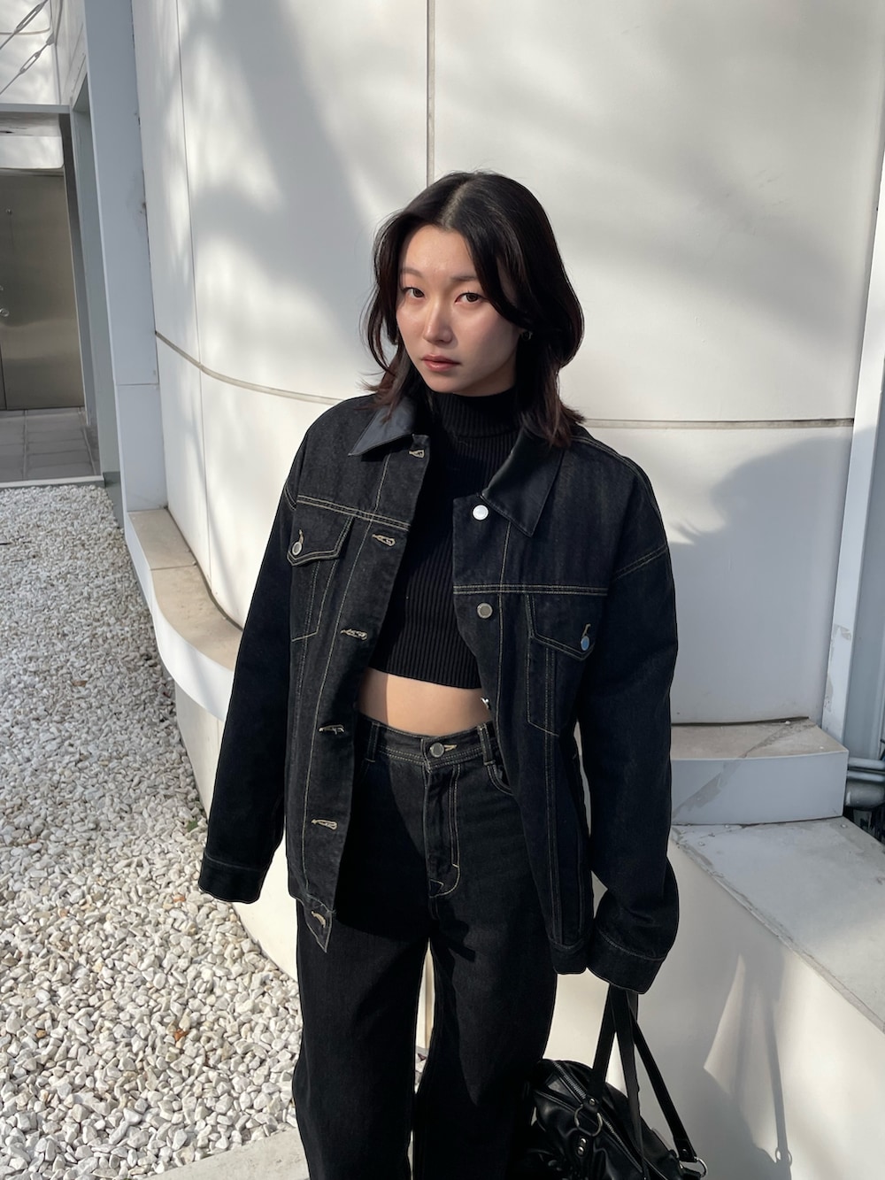 ブラック系のニット/セーター、ブルー系のブルゾン、ブルー系のデニムパンツを着用したレディースの冬コーディネートの4枚目の写真