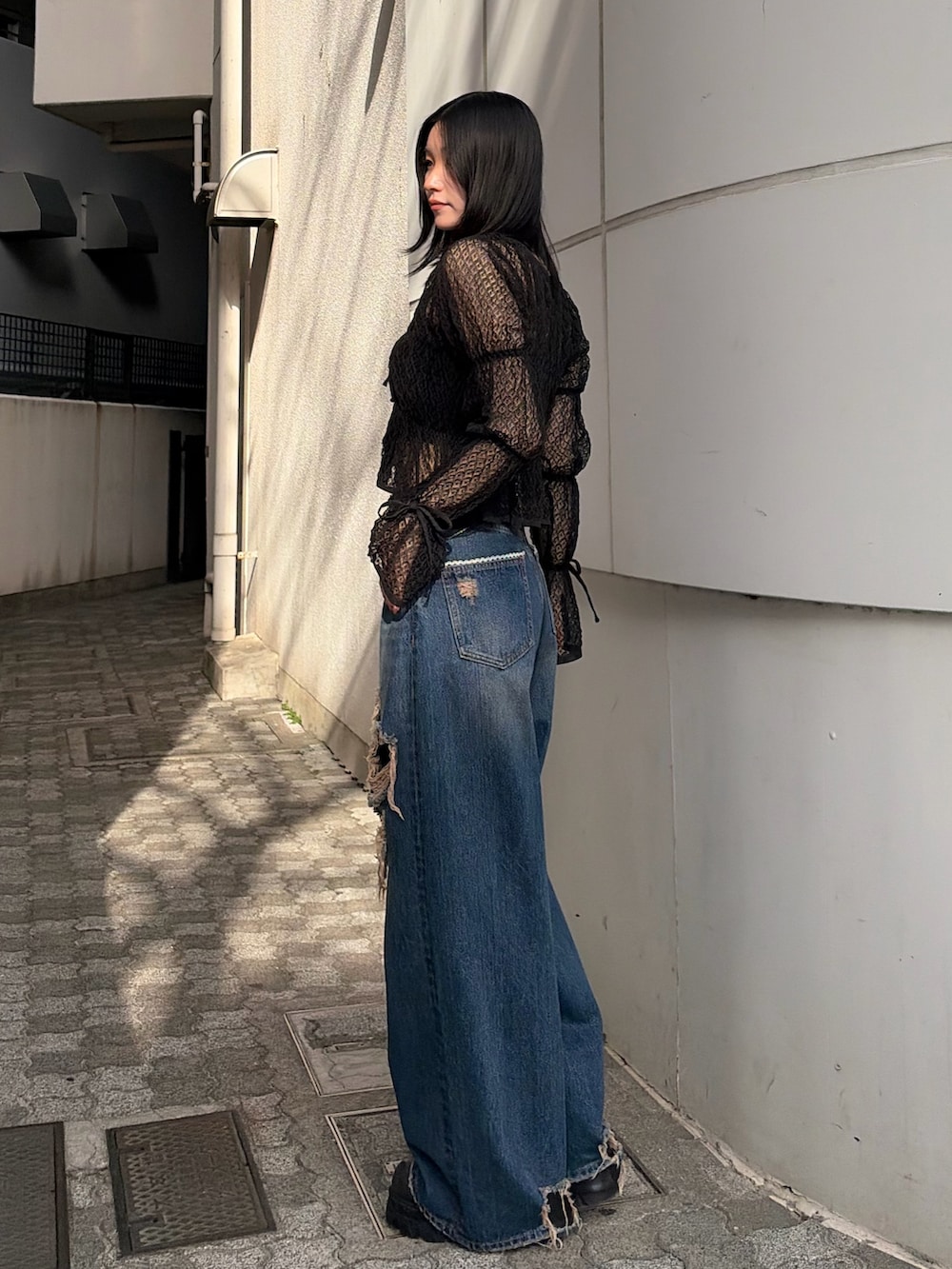 ブラック系のニット/セーター、ブルー系のデニムパンツ、ブラック系のブーツを着用したレディースの春コーディネートの3枚目の写真