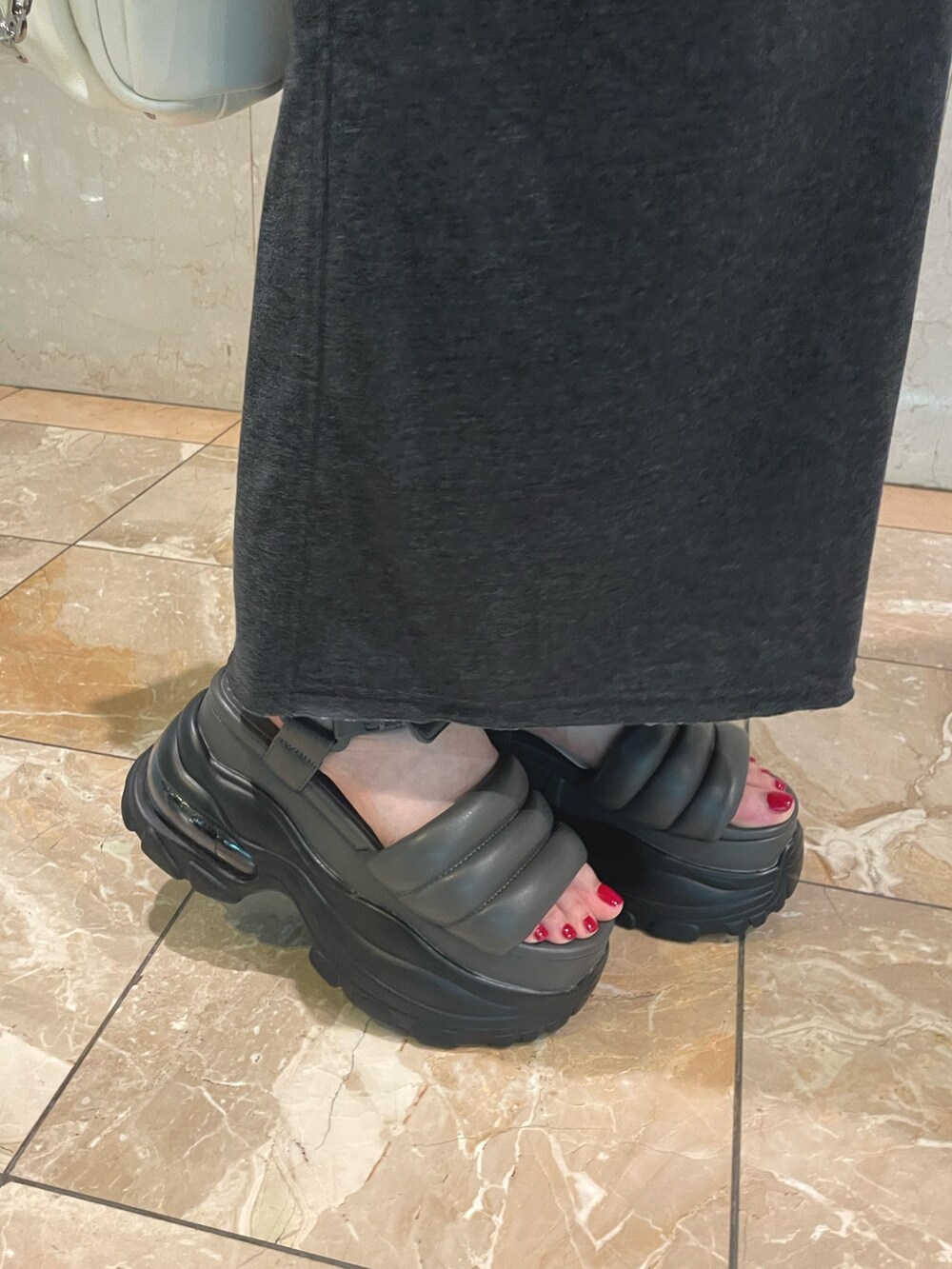 ホワイト系のニット/セーター、ブラック系のスカート、ホワイト系のハンドバッグを着用したレディースの夏コーディネートの6枚目の写真