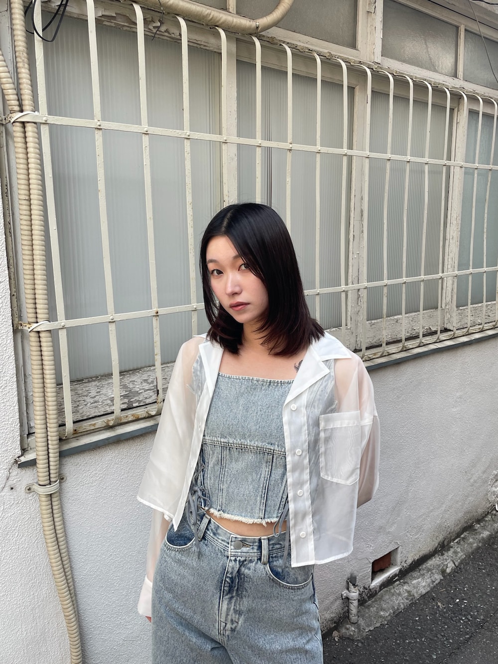 ブルー系のタンクトップ、ブルー系のデニムパンツ、ホワイト系のスニーカーを着用したレディースの春コーディネートの4枚目の写真