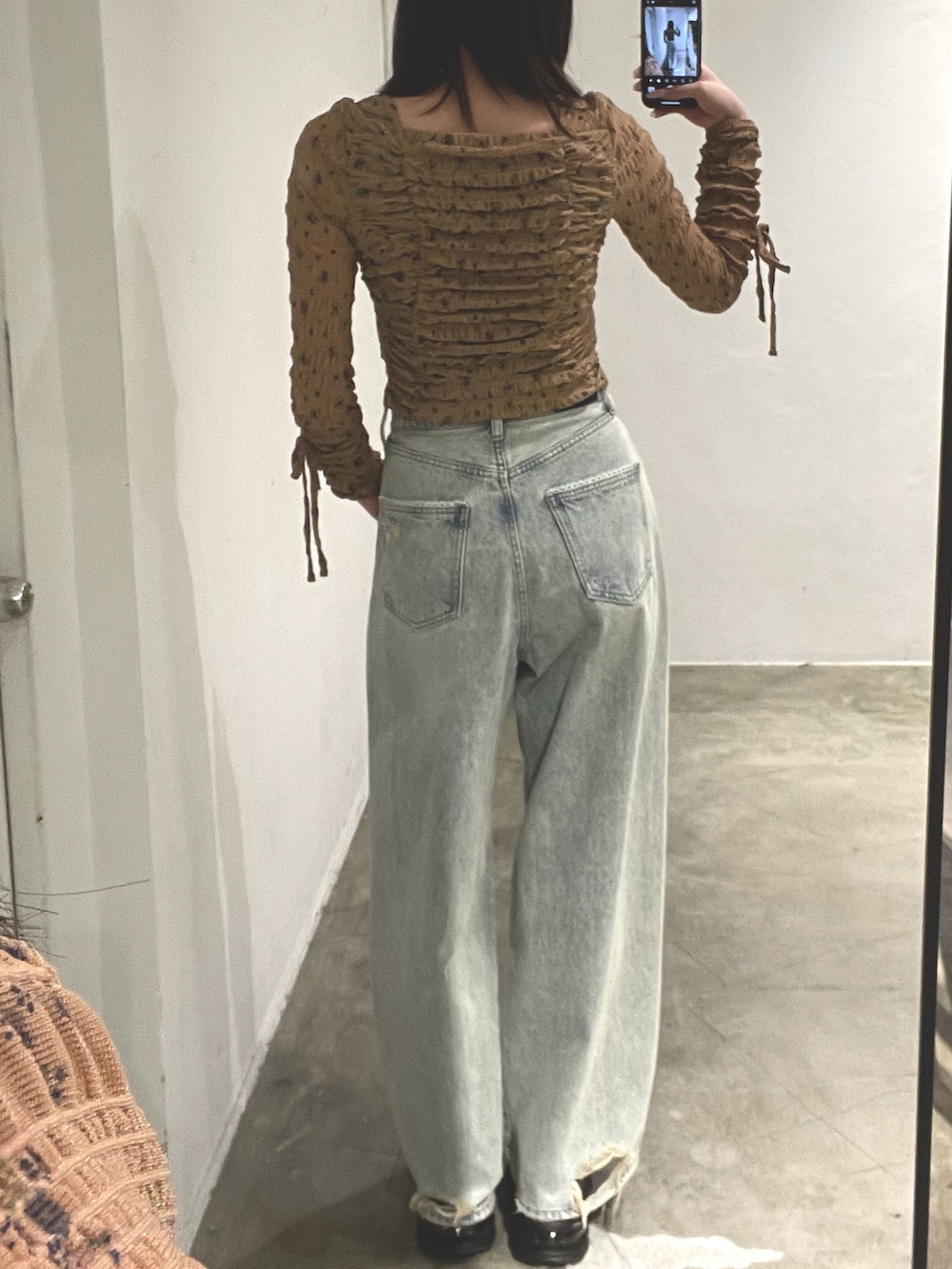 ベージュ系のTシャツ/カットソー、ブルー系のデニムパンツ、ブラック系のスニーカーを着用したレディースの冬コーディネートの3枚目の写真