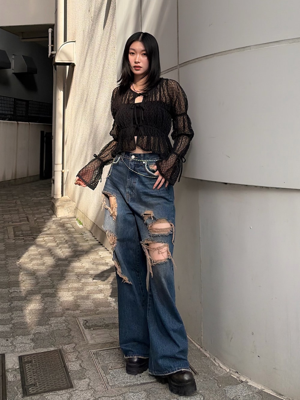 ブラック系のニット/セーター、ブルー系のデニムパンツ、ブラック系のブーツを着用したレディースの春コーディネートの2枚目の写真