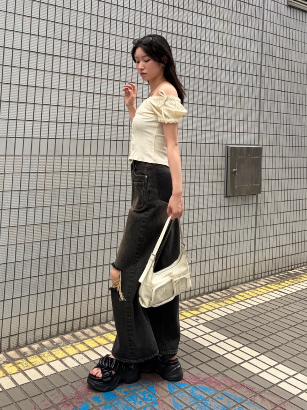ブラック系のサンダル、ホワイト系のハンドバッグ、ホワイト系のTシャツ/カットソーを着用したレディースの夏コーディネートの2枚目の写真