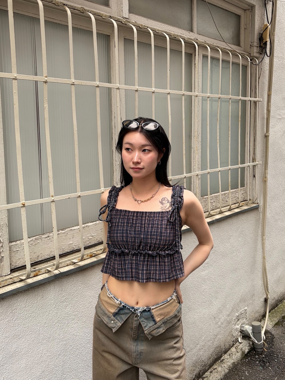 ブラウン系のタンクトップ、ブラウン系のデニムパンツ、ブラック系のサンダルを着用したレディースの夏コーディネートの5枚目の写真