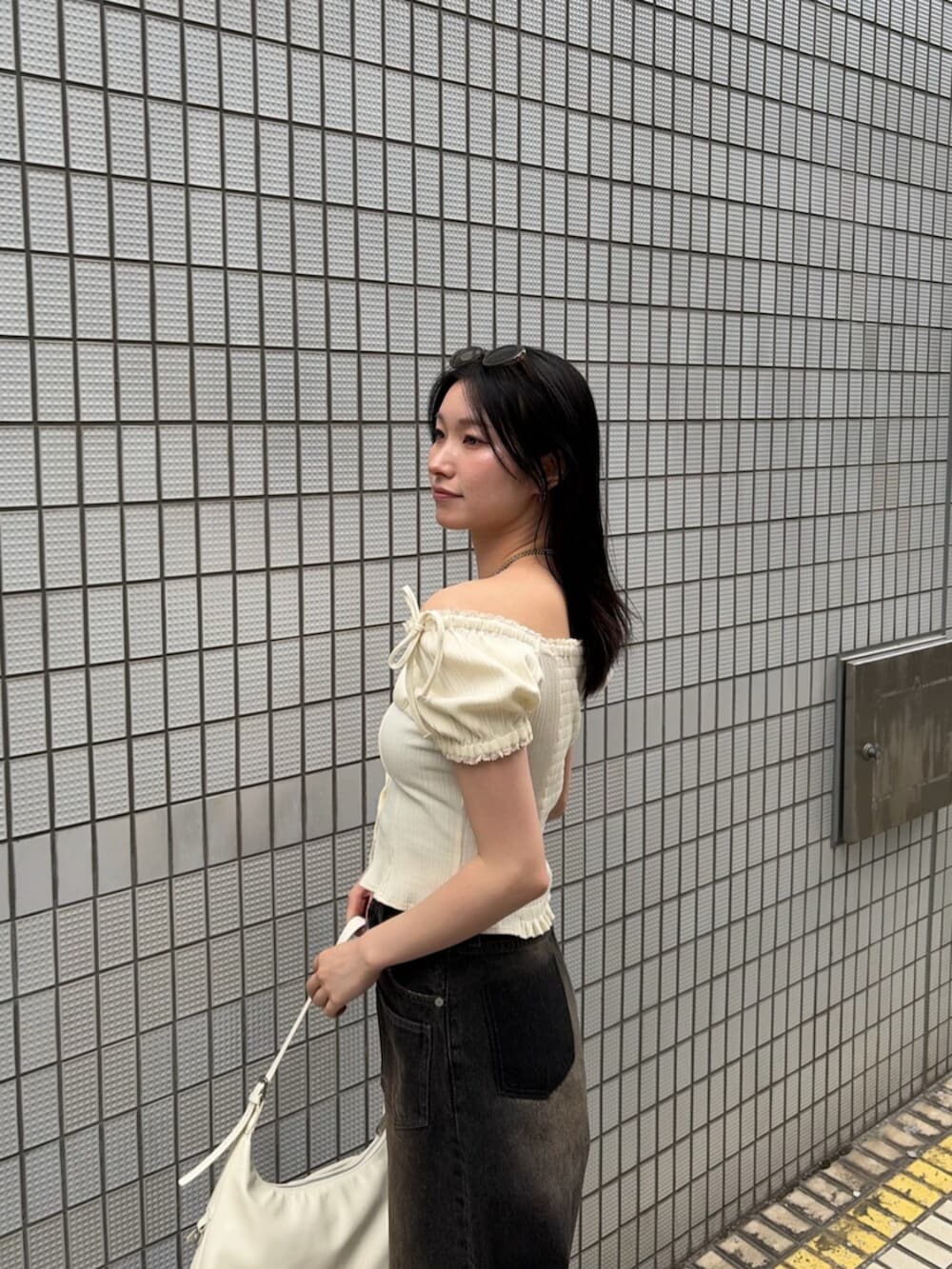 ブラック系のサンダル、ホワイト系のハンドバッグ、ホワイト系のTシャツ/カットソーを着用したレディースの夏コーディネートの6枚目の写真