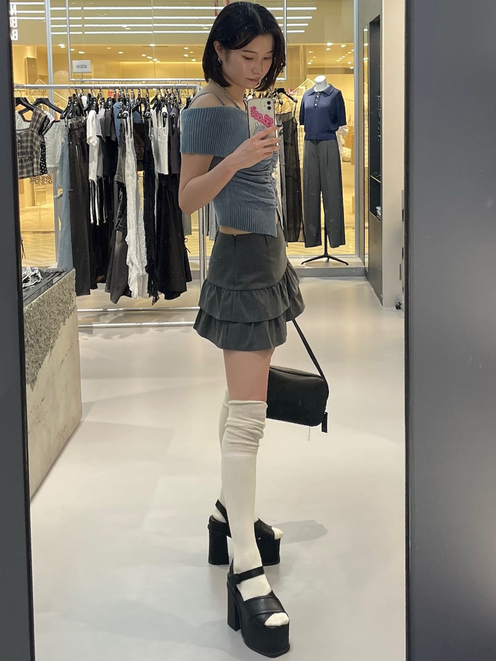 ブルー系のニット/セーター、グレー系のスカート、ブラック系のサンダルを着用したレディースの夏コーディネートの2枚目の写真