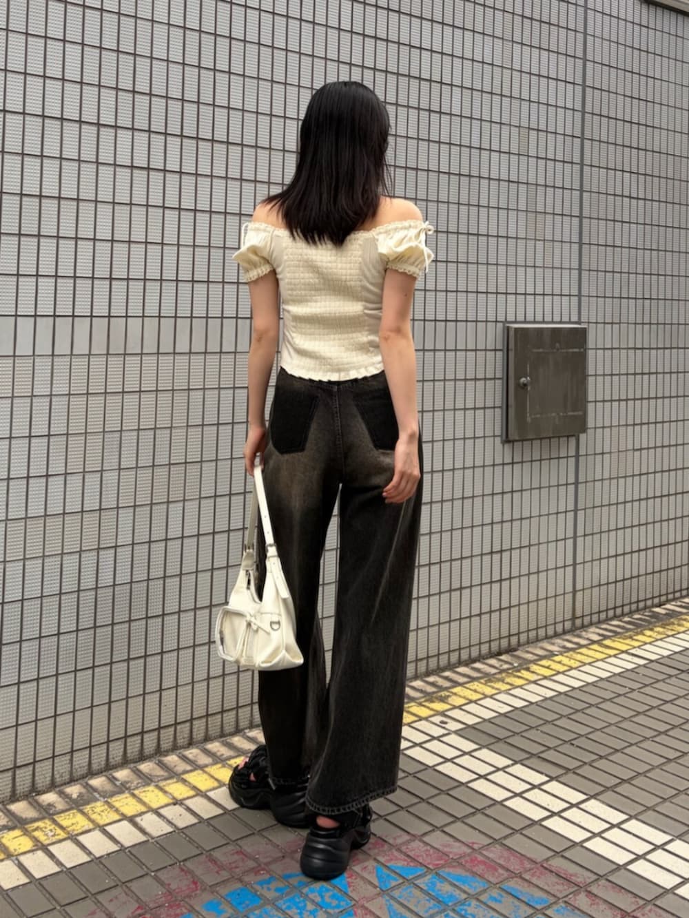 ブラック系のサンダル、ホワイト系のハンドバッグ、ホワイト系のTシャツ/カットソーを着用したレディースの夏コーディネートの3枚目の写真