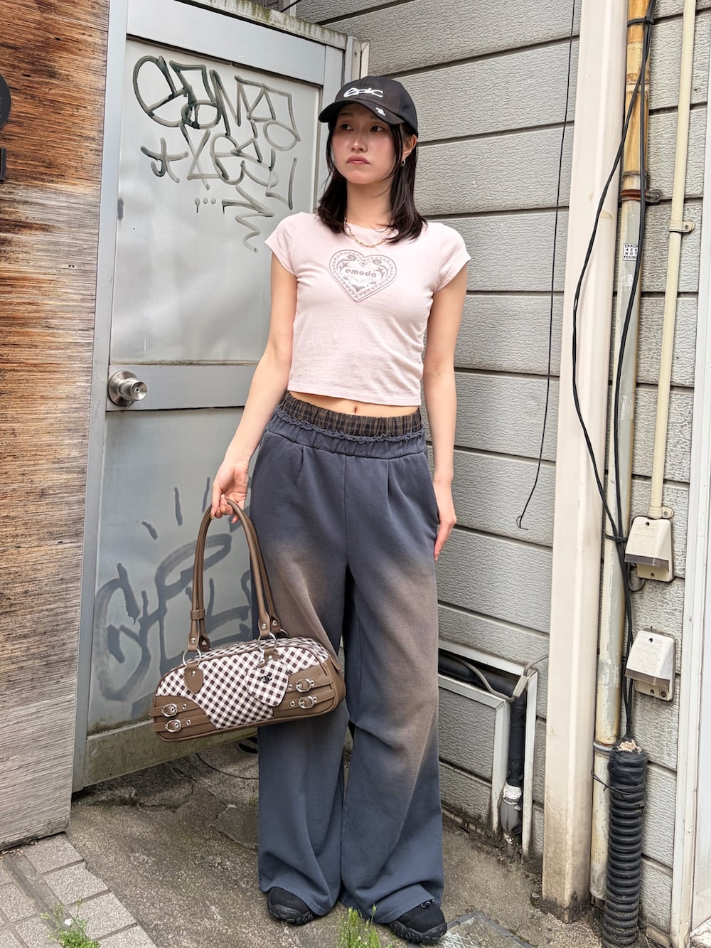 ブラウン系のハンドバッグ、ピンク系のTシャツ/カットソー、ブルー系のスウェットパンツを着用したレディースの春コーディネートの2枚目の写真
