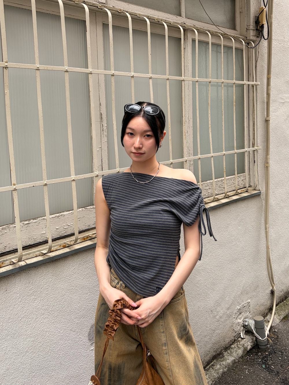グレー系のTシャツ/カットソー、ブラウン系のショルダーバッグ、ベージュ系のデニムパンツを着用したレディースの夏コーディネートの4枚目の写真