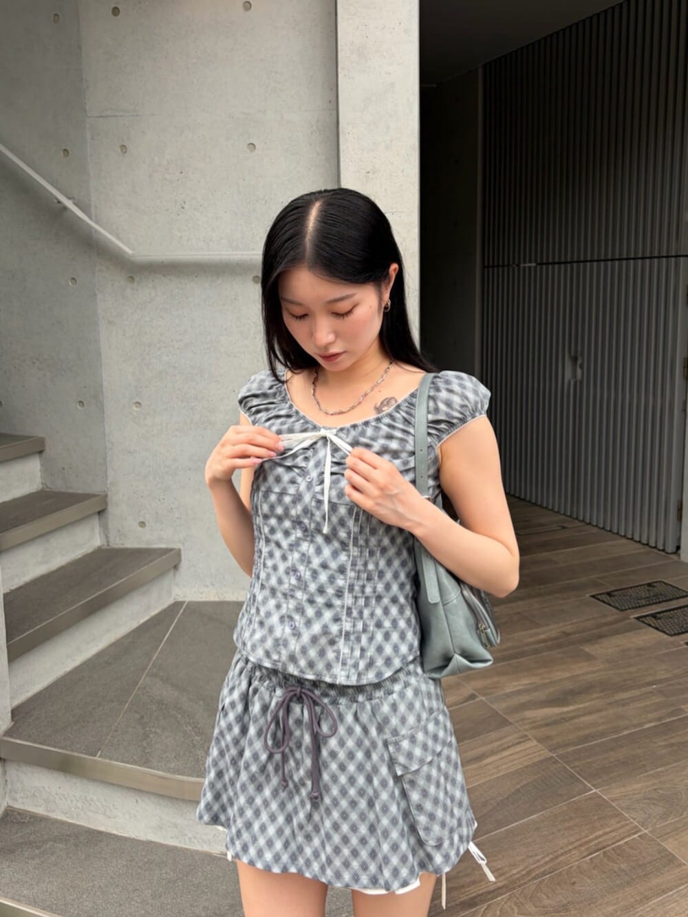 ブラック系のサンダル、ブルー系のハンドバッグ、ブルー系のシャツ/ブラウスを着用したレディースの夏コーディネートの6枚目の写真