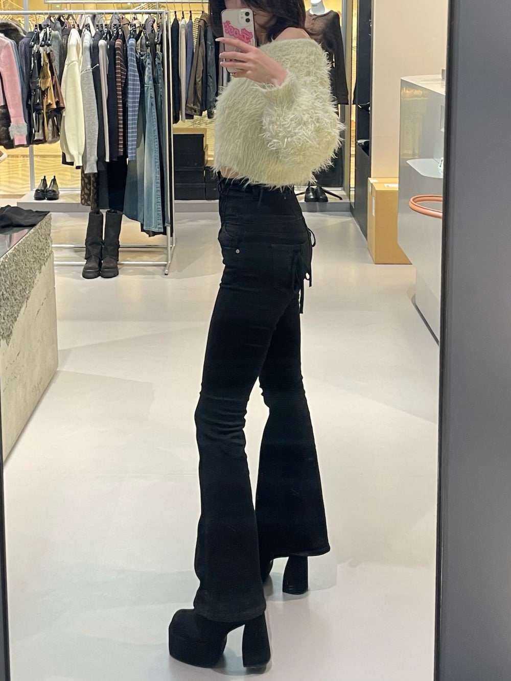 ホワイト系のニット/セーター、ブラック系のデニムパンツ、ブラック系のブーツを着用したレディースの冬コーディネートの2枚目の写真