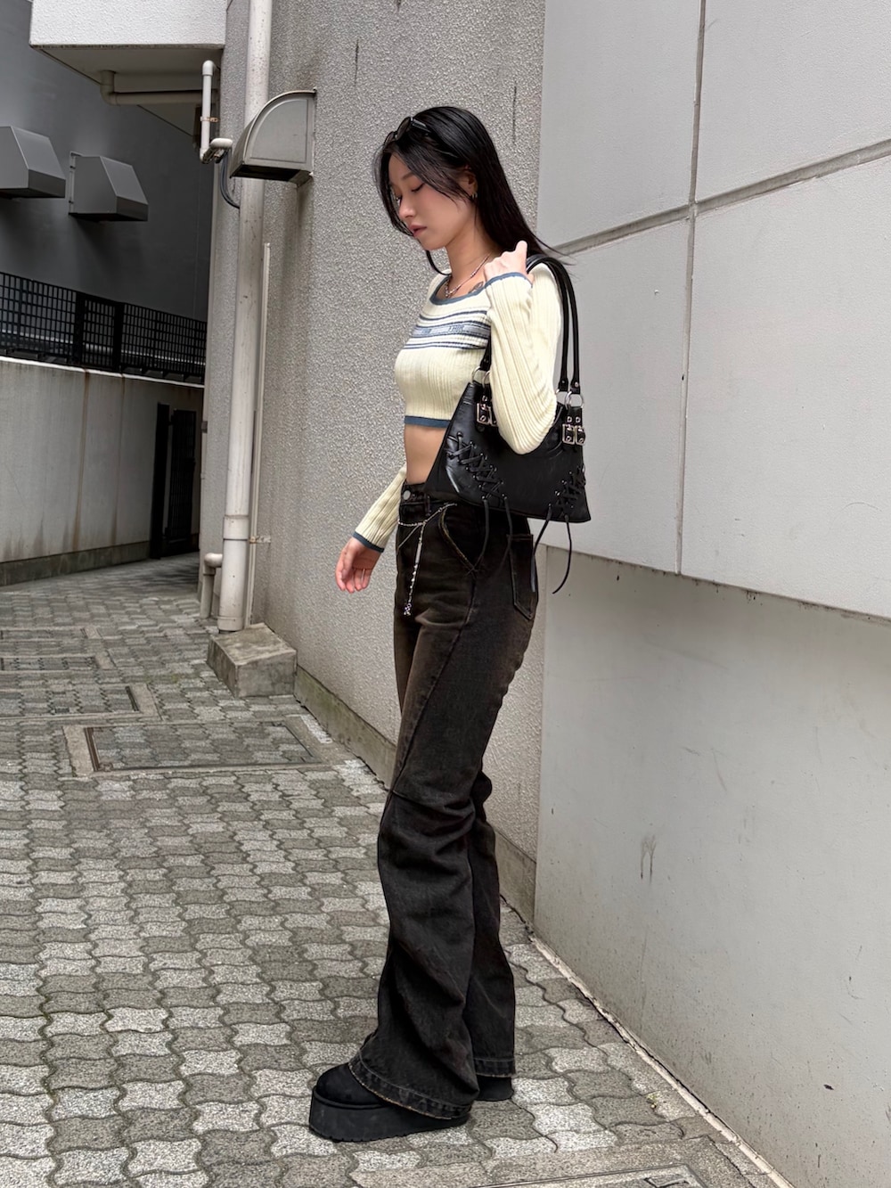 ホワイト系のニット/セーター、ブラック系のショルダーバッグ、ブラック系のデニムパンツを着用したレディースの秋コーディネートの2枚目の写真