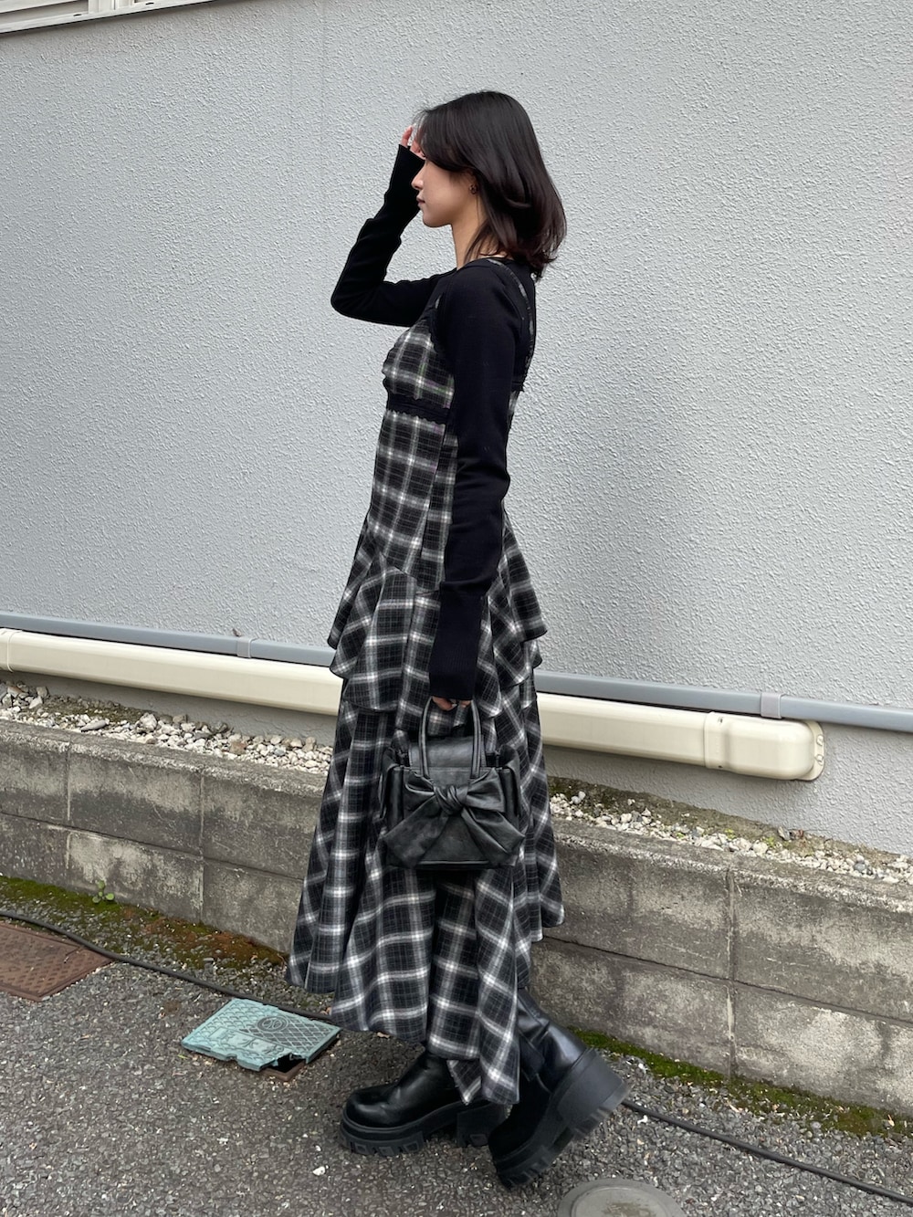 ブラック系のニット/セーター、ブラック系のワンピース、ブラック系のハンドバッグを着用したレディースの冬コーディネートの2枚目の写真