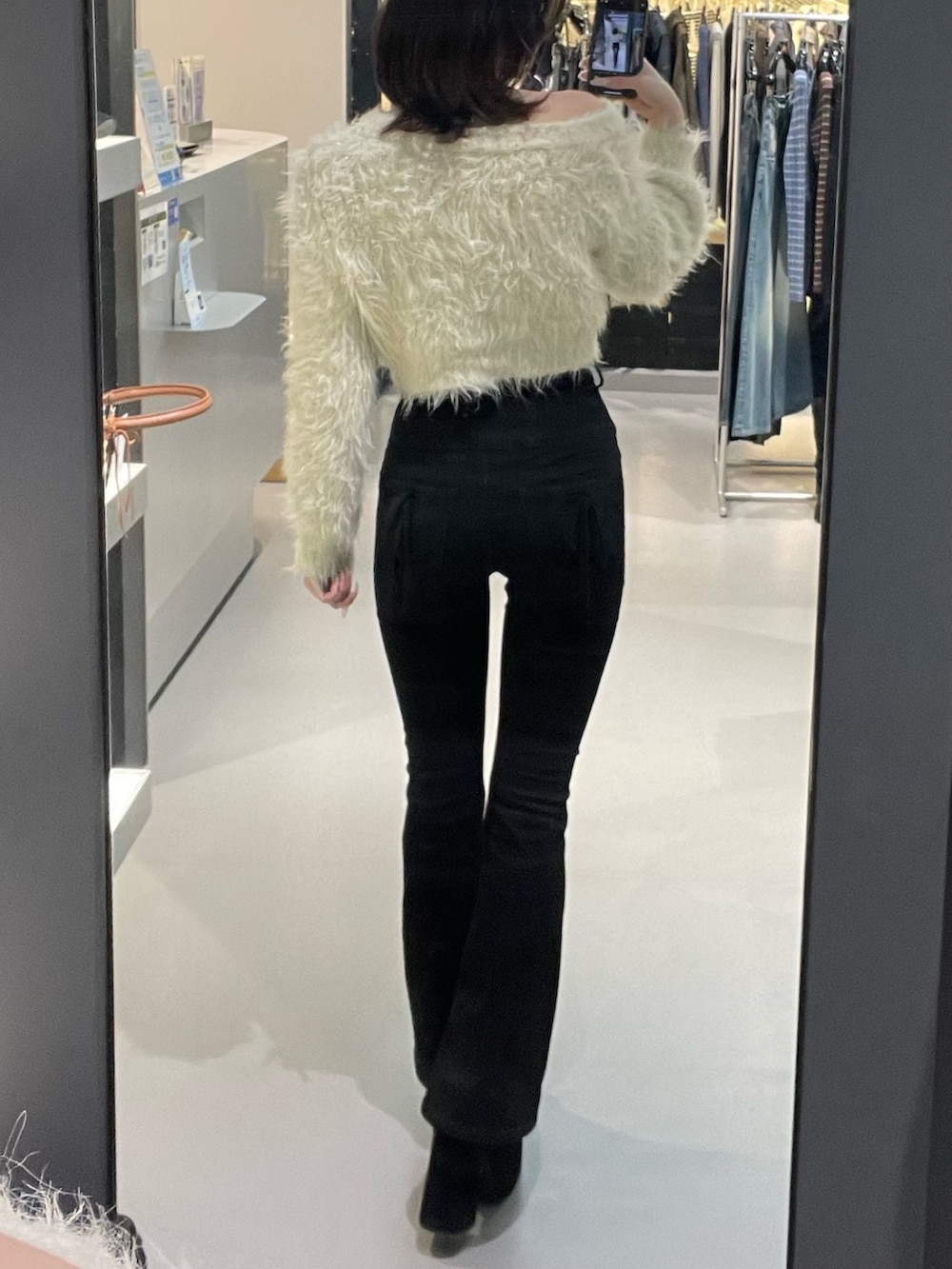 ホワイト系のニット/セーター、ブラック系のデニムパンツ、ブラック系のブーツを着用したレディースの冬コーディネートの3枚目の写真