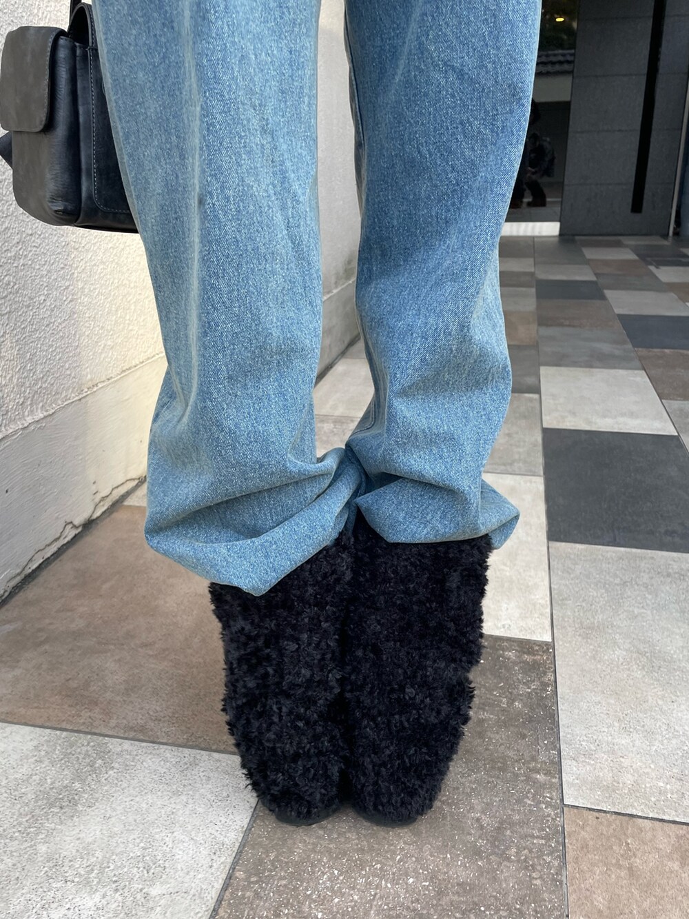 ブラック系のニット/セーター、ブルー系のデニムパンツ、ブラック系のブーツを着用したレディースの冬コーディネートの6枚目の写真